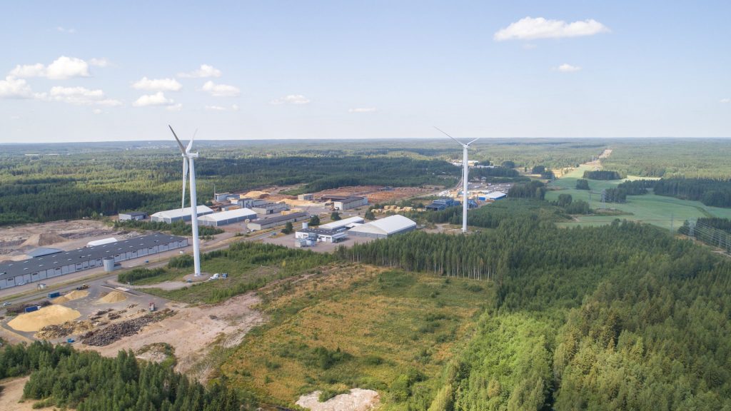 Mäkelänkankaan teollisuusalue. Tuulivoimaloita ja aurinkopaneeleita, ympärillä metsämaisemaa.