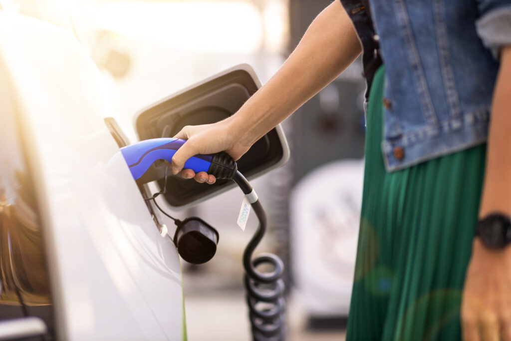 Ihminen laittaa sähköauton latauskaapelia autoon.