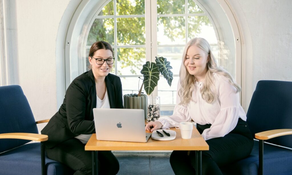 Sijoittumispalvelumme auttaa alueelle sijoittuvia yrityksiä. Kuvassa kaksi henkilöä tietokoneen äärellä, taustalla ikkuna ja merimaisema.